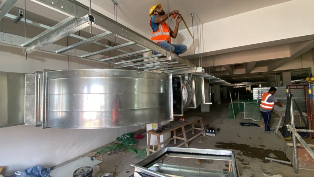 HVAC ductwork installation crew measuring and coordinating on a commercial construction site